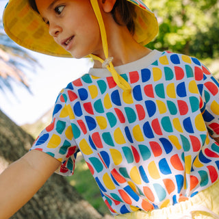Toddler wearing a bright printed t-shirt and matching sunhat outdoors