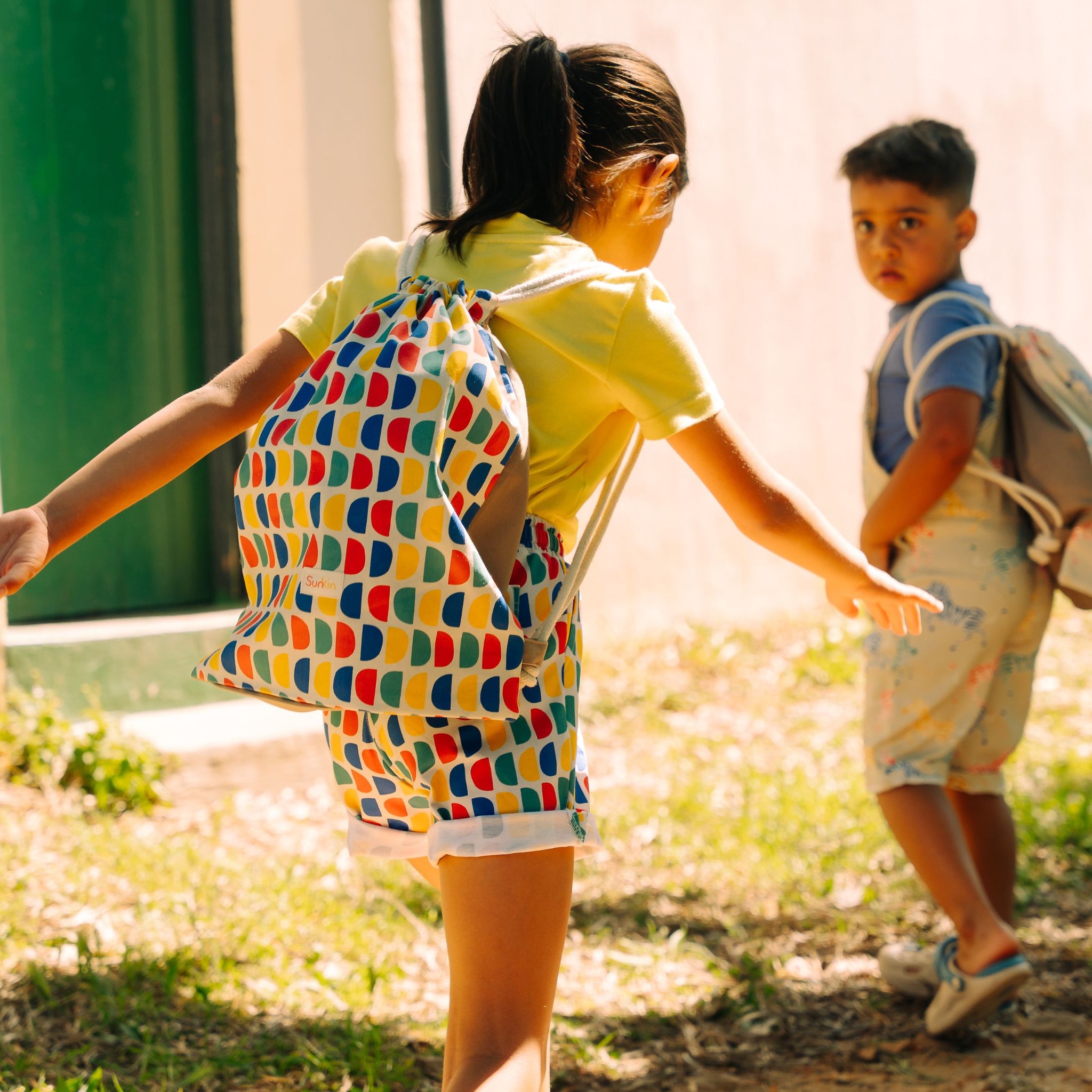 Young girl walking wearing a drawstring bag in bright print and matching shorts