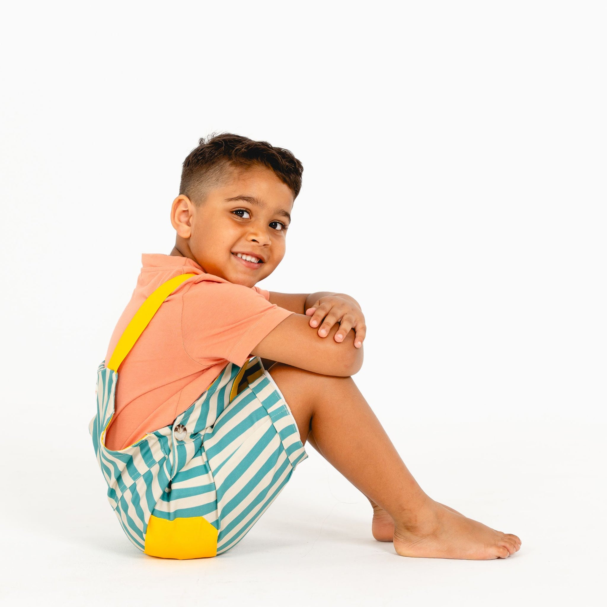 Boy wearing striped green with pops of bright yellow shortarees by SunKin and apricot tshirt