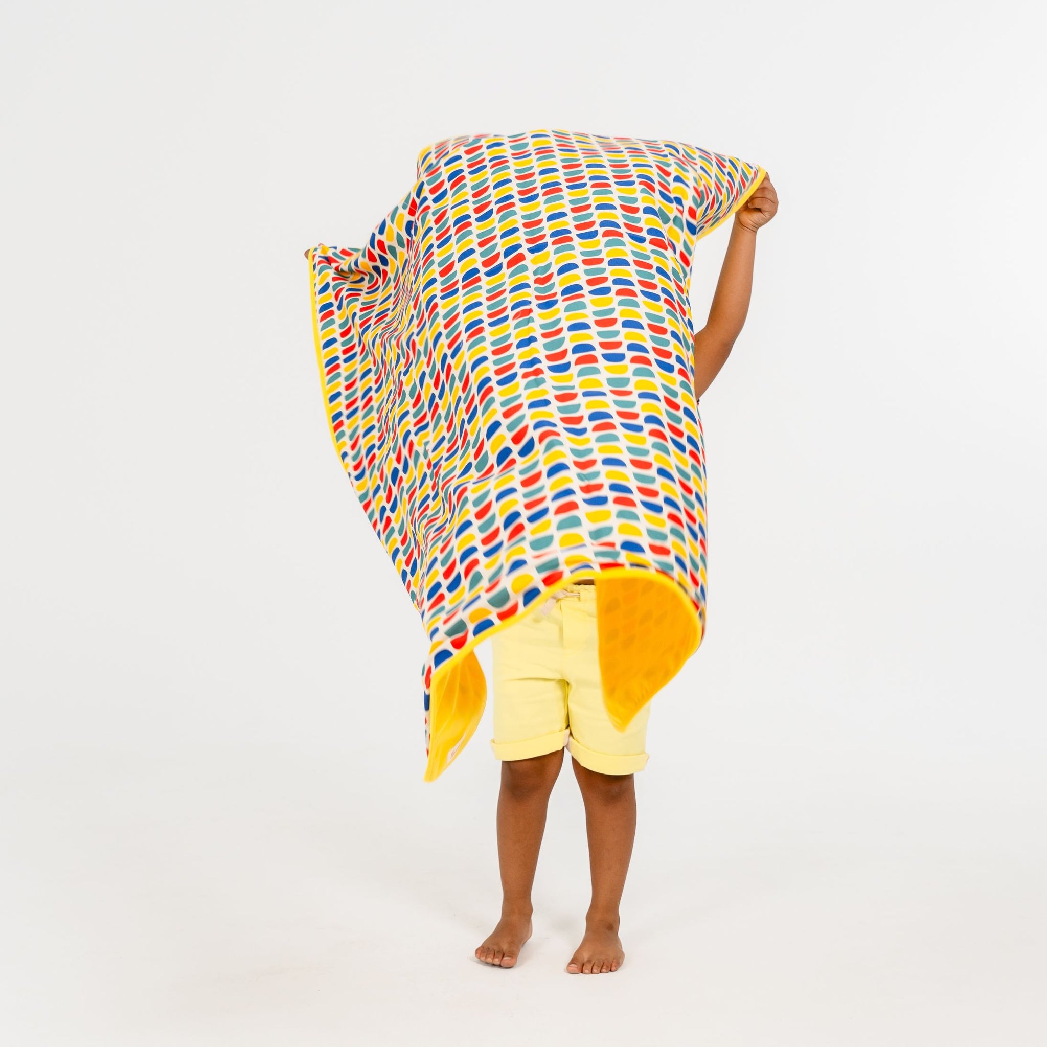 Child laying down a bright printed sun blanket 