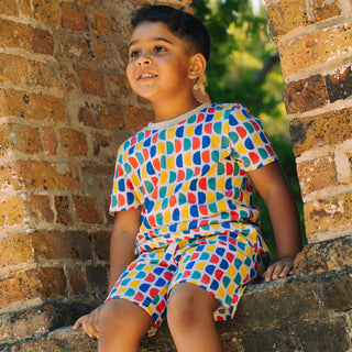 Boy wearing bright summer shorts in D print UV blocking