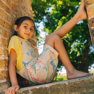 Child sitting on brick wall with one leg up wearing zebra print shortaree