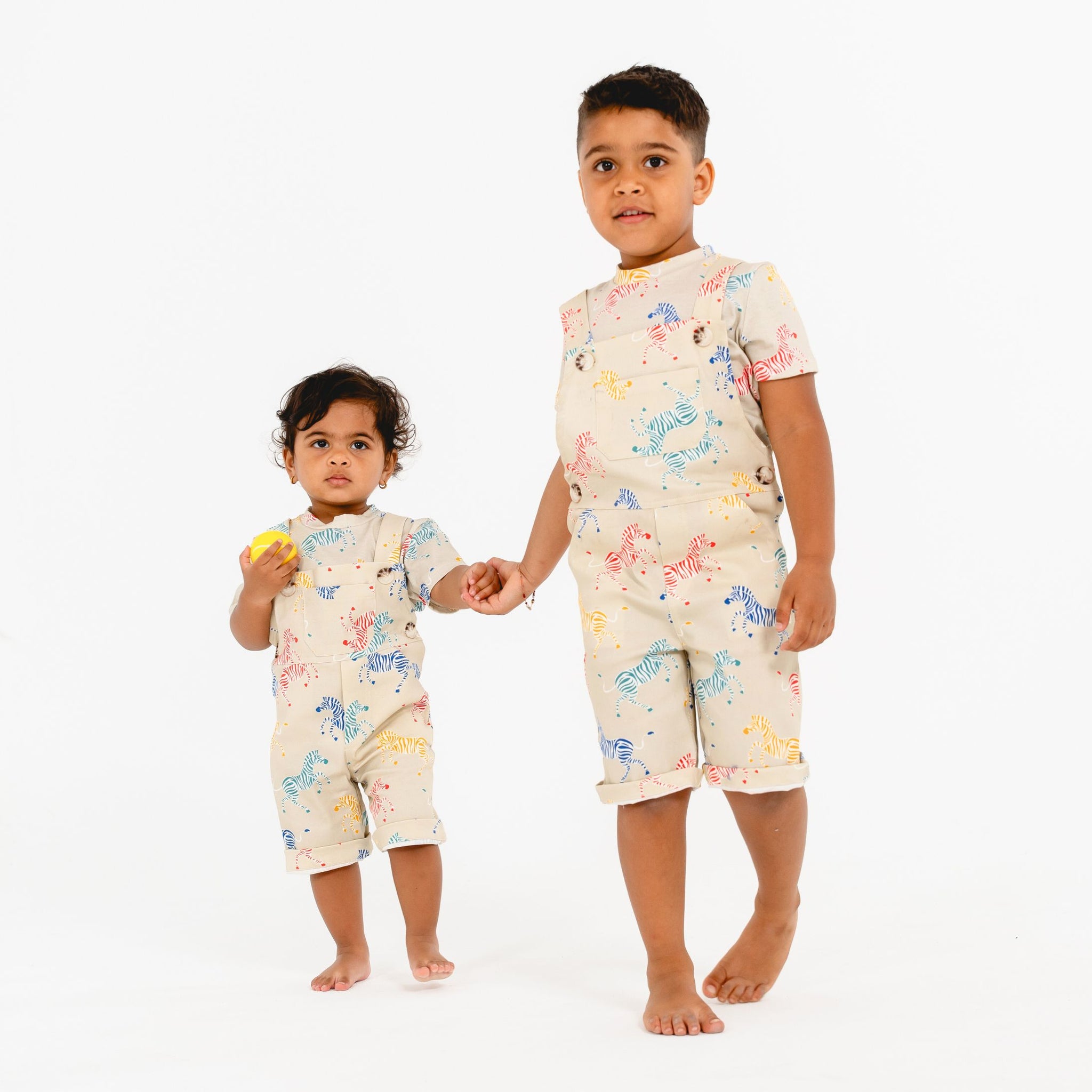 Siblings wearing matching outfits by SunKin holding hands