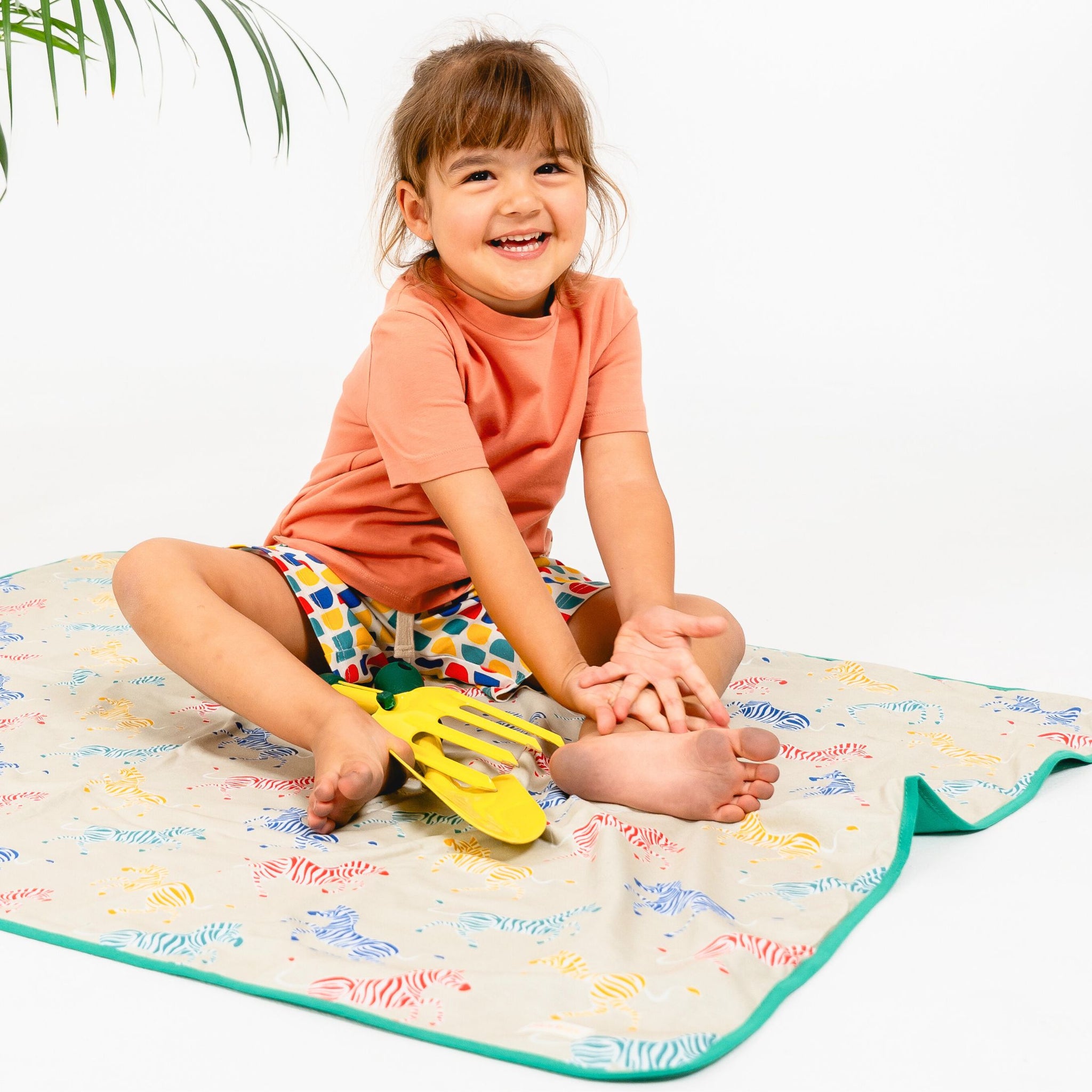 Girl sitting on a Sunkin sun blanket for summer essentials
