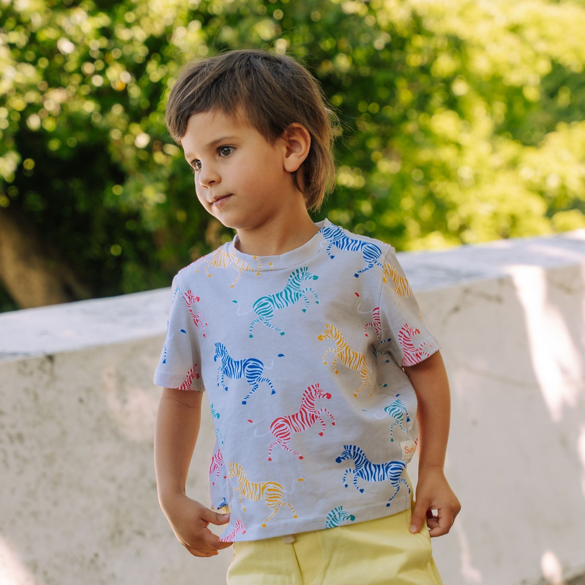 Toddler wearing UV blocking tshirt in zebra print in a park on sunny day