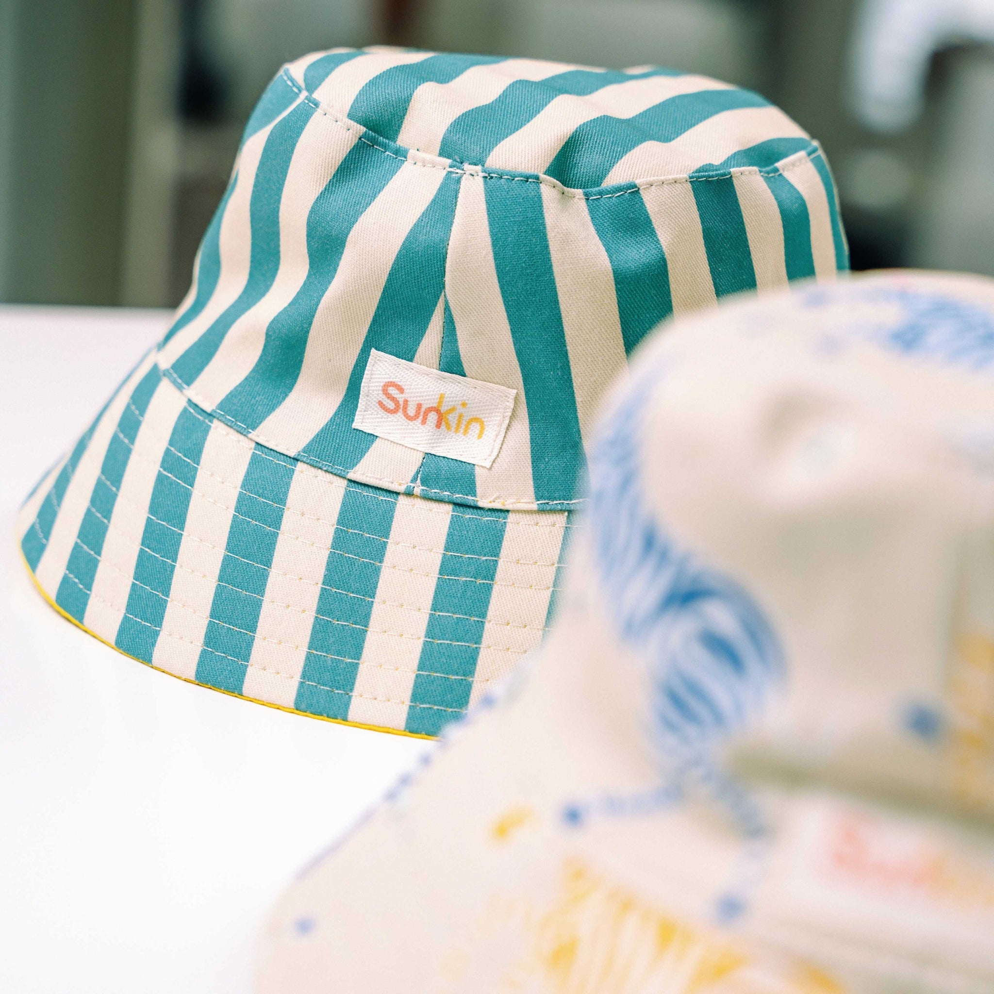 Green and oyster striped bucket hat with SunKin label