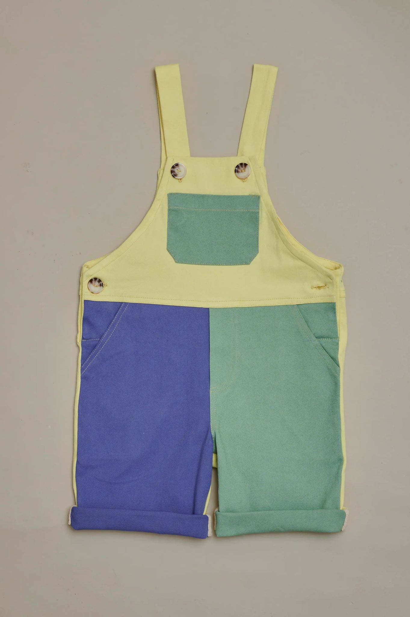 Front view of SunKin’s UPF50+ multicolour kids dungarees—patchwork shortaree with adjustable straps and contrast trim.