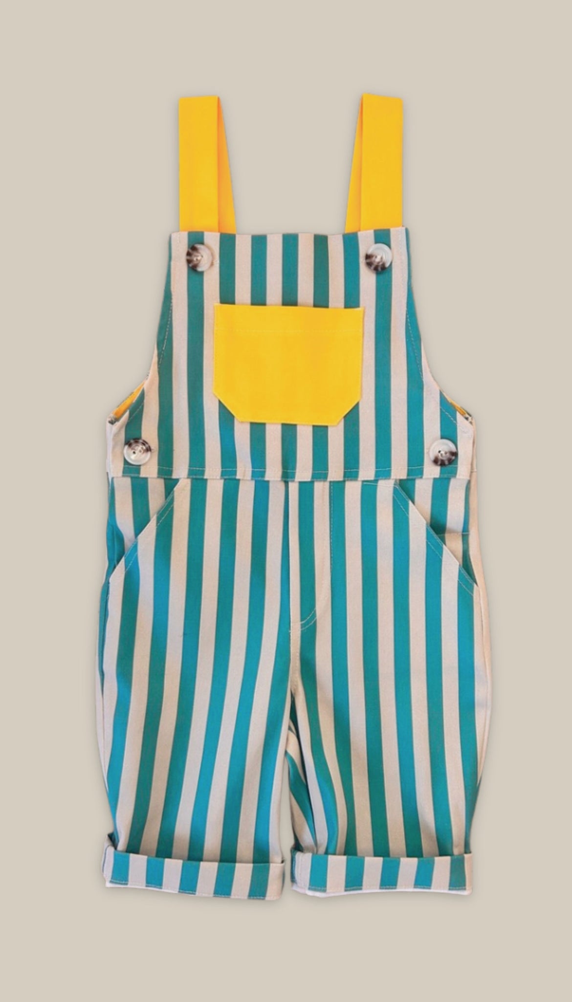 Front view of green striped overalls with a yellow pocket on a beige background