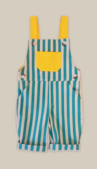 Front view of green striped overalls with a yellow pocket on a beige background