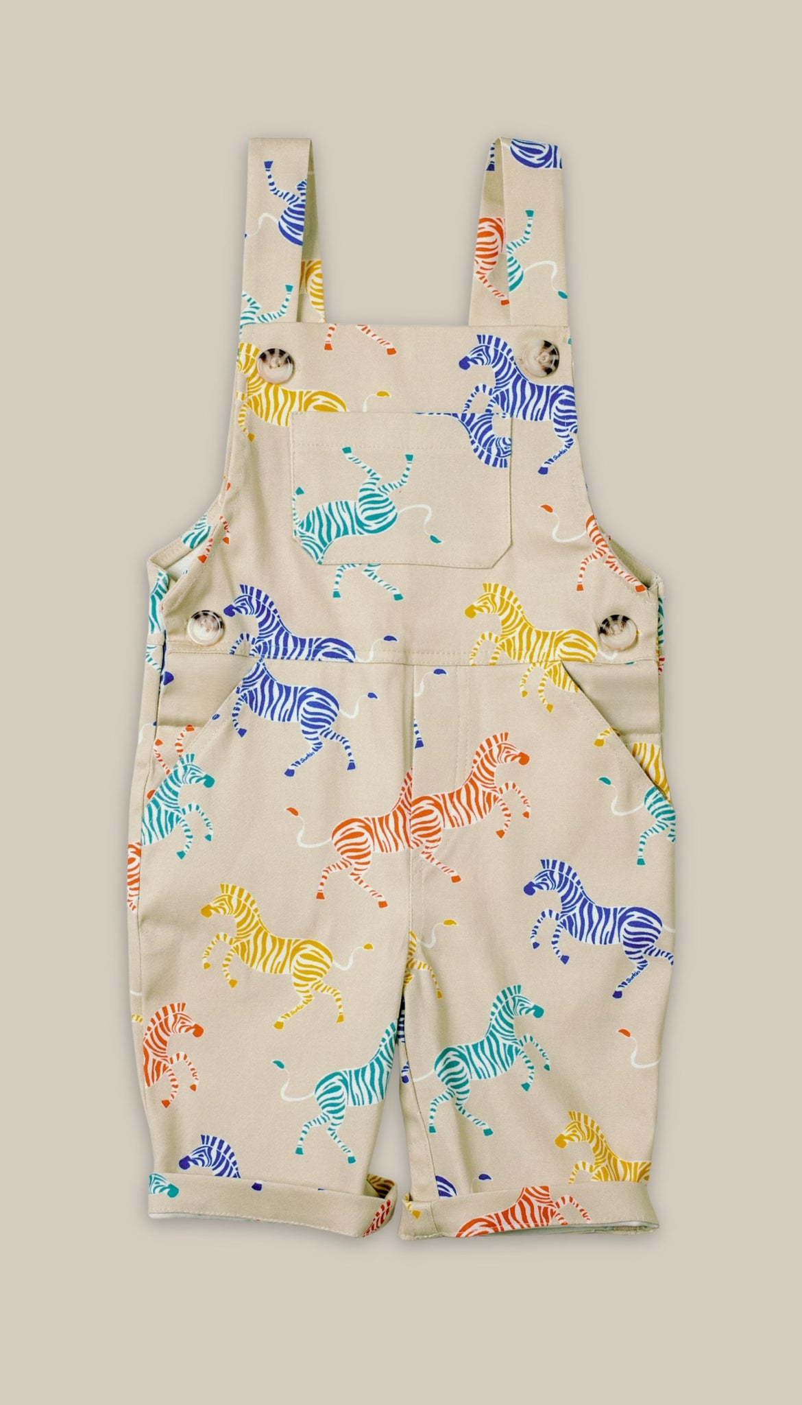 Children's overalls with colorful zebra pattern on a beige background